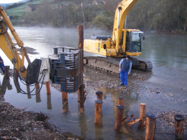 Maquinaria colocando troncos de eucalipto a orillas del río