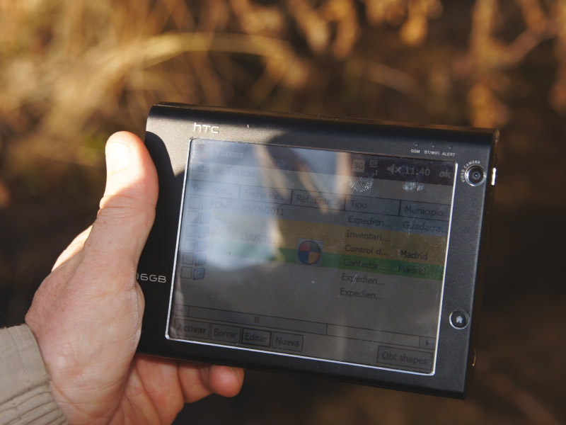 Dispositivo móvil en la mano del técnico con Geocampo en la pantalla