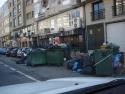 Calle con basura por el suelo y contenedores repletos
