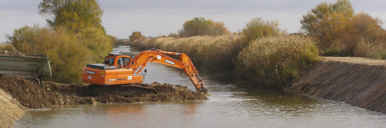 Excavadora drenando un canal