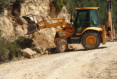 Excavadora retirando rocas del camino agrario. 