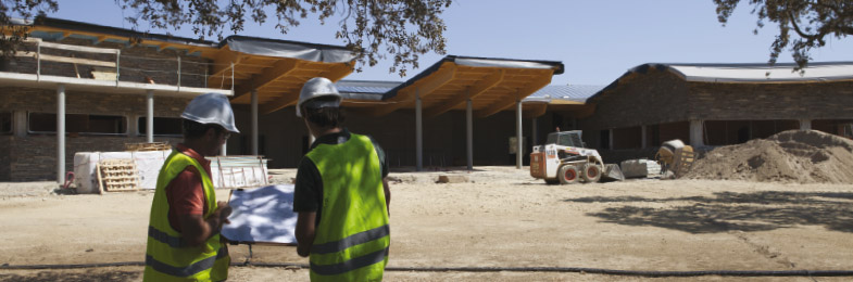 Arquitectos revisando planos delante de edificio en construcción