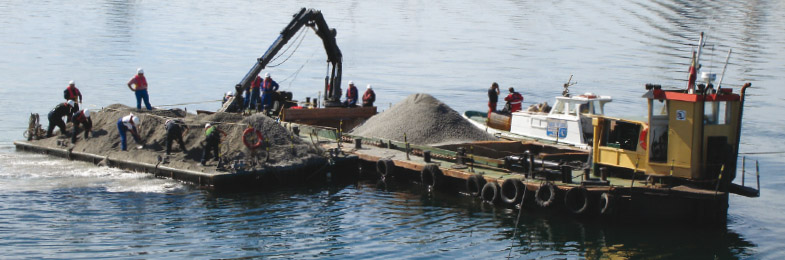 Trabajadores extendiendo manualmente áridos para la regeneración banco marisquero As Piras en El Ferrol